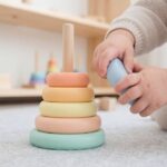 Un enfant joue avec un anneau empilable coloré sur un tapis