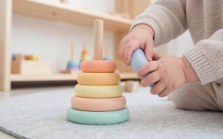 Un enfant joue avec un anneau empilable coloré sur un tapis