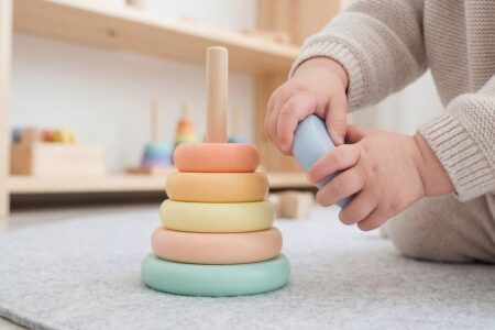 Un enfant joue avec un anneau empilable coloré sur un tapis