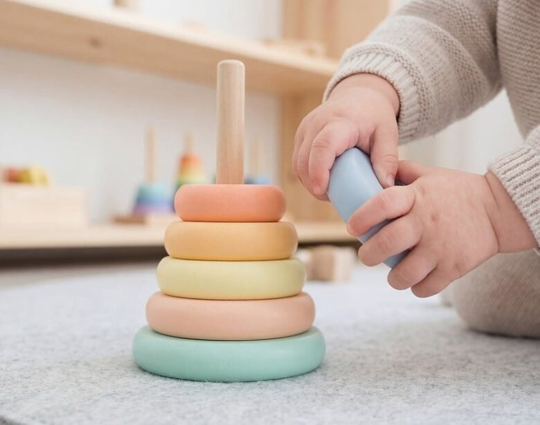 Un enfant joue avec un anneau empilable coloré sur un tapis