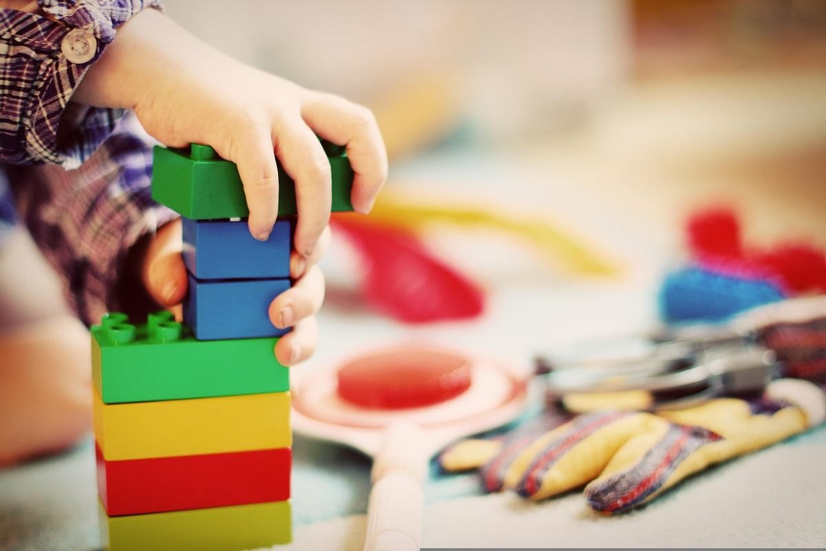 Enfant construit une tour de briques colorées sur une table Enfant construit une tour de briques colorées sur une table