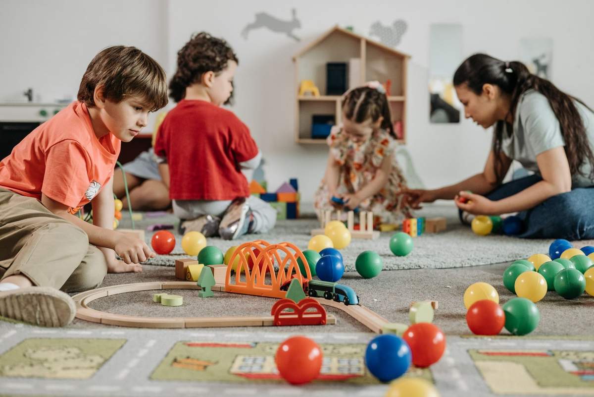 Enfants et adulte jouent avec des jouets sur un tapis coloré Enfants et adulte jouent avec des jouets sur un tapis coloré