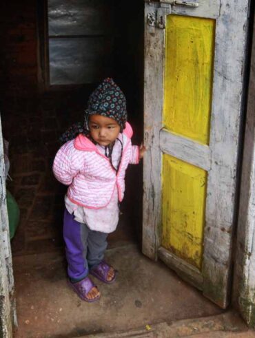 Petit enfant habillé chaudement, debout dans l'encadrement d'une porte