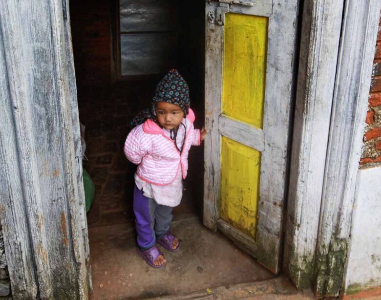 Petit enfant habillé chaudement, debout dans l'encadrement d'une porte